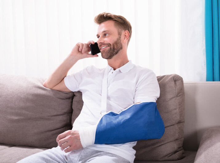 Mann mit gebrochenem Arm telefoniert glücklich