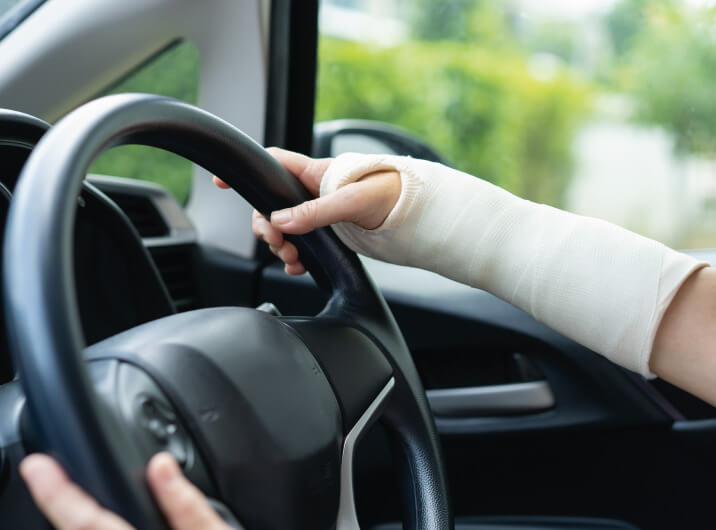 Person fährt mit gebrochenem Arm Auto